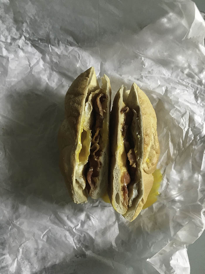 The cross section of the classic NYC bacon egg and cheese on a roll