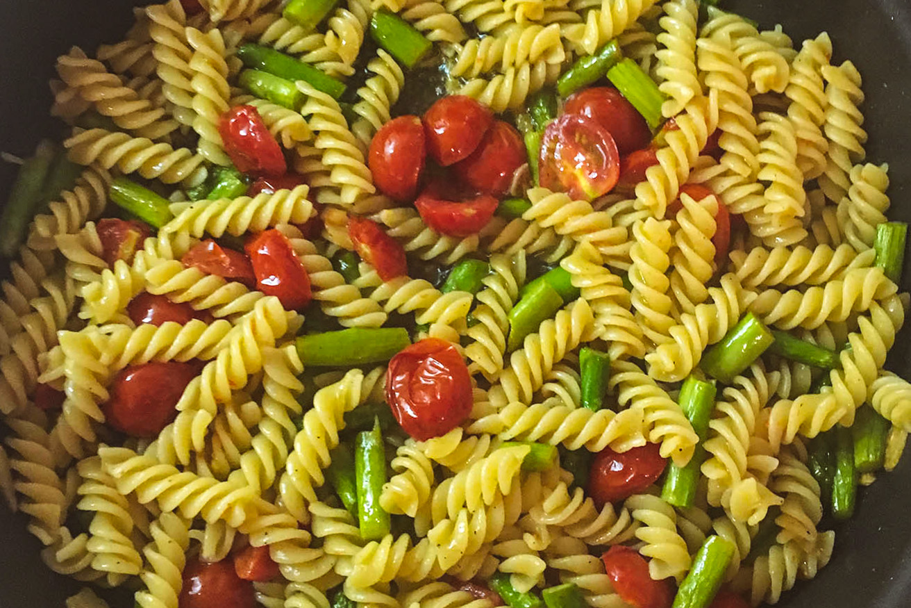 Summer asparagus, cherry tomato, garlic and oil pasta with basil and mint in a cast-iron pan
